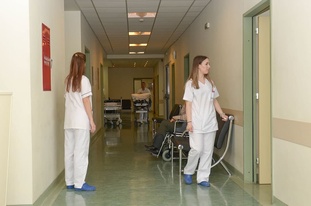 Nursing staff attending to a patient in the ward corridor